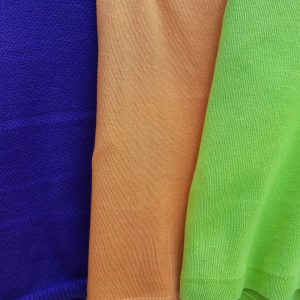 Foto van drie kledingstukken met felle kleuren bij het gedicht "Combineren" van Marianne Nan.