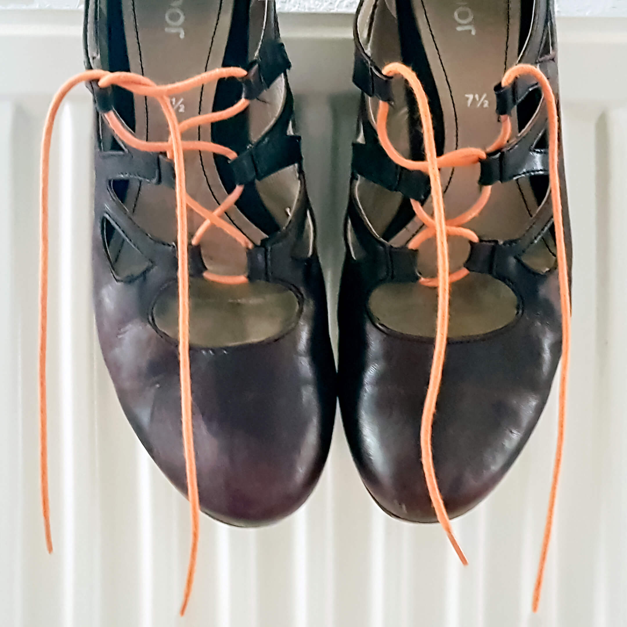 Foto van paarsige schoenen met oranje veters op een verwarming bij het gedicht "Oranje 3".